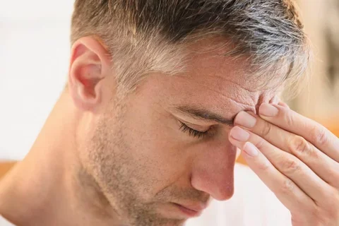 Man touching forehead in discomfort