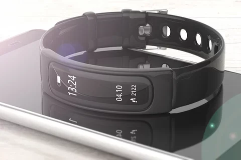 A black smart watch lies on top of a smart phone