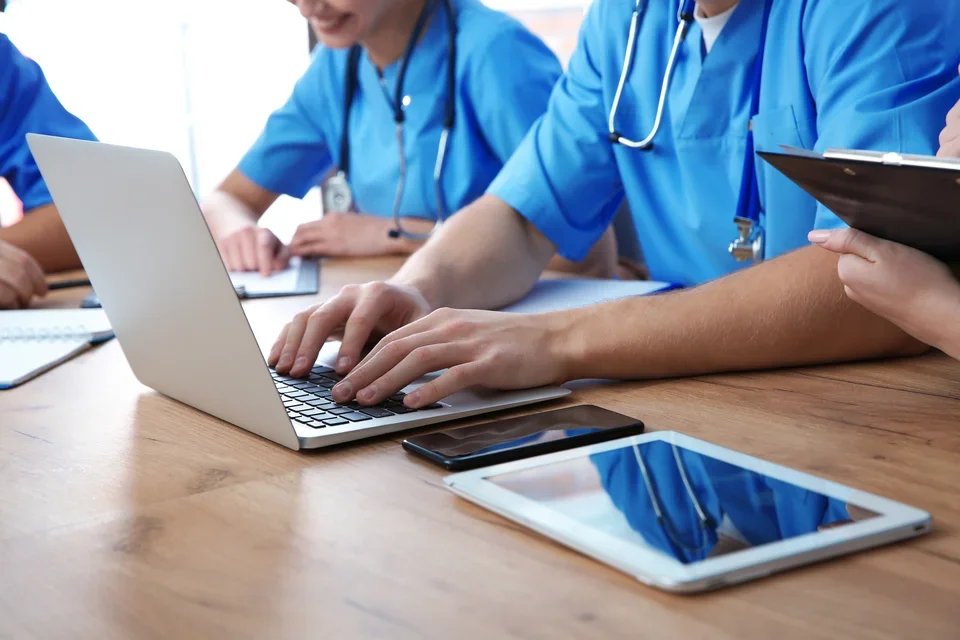 Clinicians working at a desk on electronic devices
