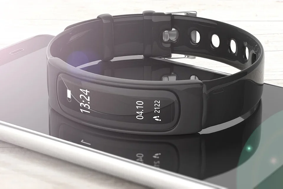 A black smart watch lies on top of a smart phone