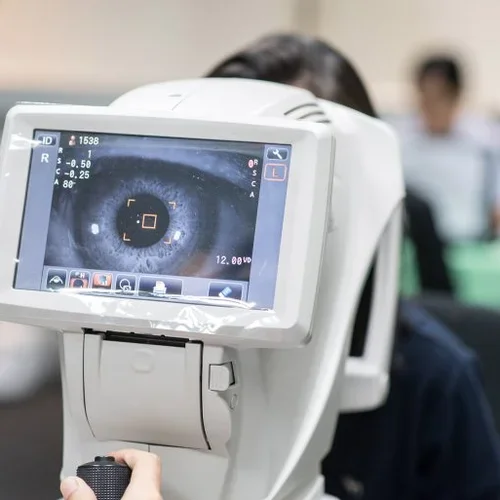 Woman looking at refractometer eye test machine in ophthalmology