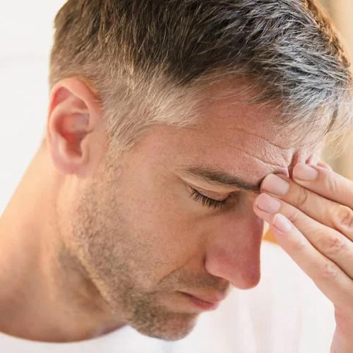 Man touching forehead in discomfort