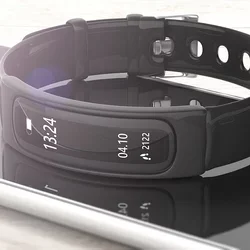 A black smart watch lies on top of a smart phone